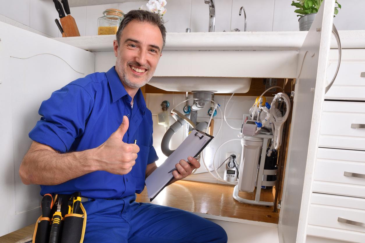 Plumbing technician checking water installation with notepad ok gesture