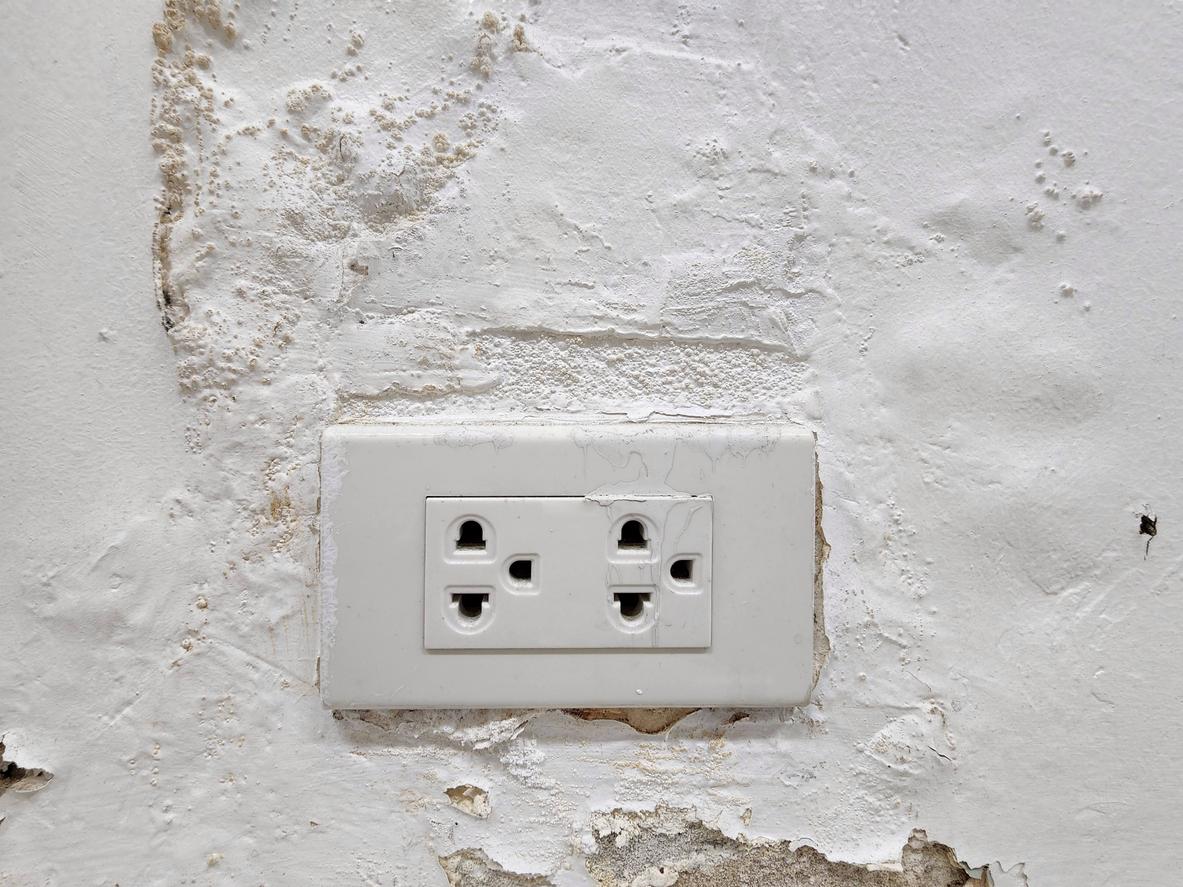 The power outlet on the cement wall that seeps with water causes the paint on the wall