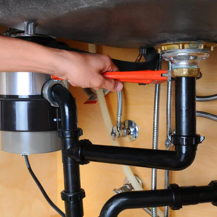 Plumber Using Wrench Under Kitchen Sink